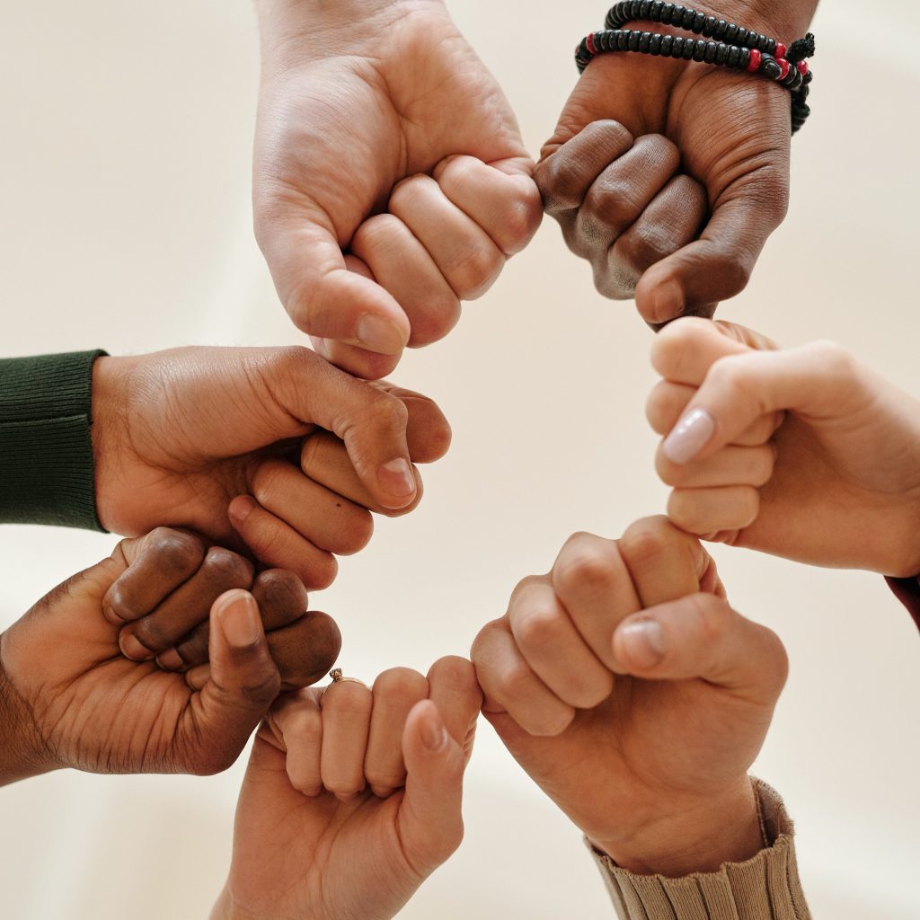 Sept mains jointes se touchent pour former un cercle et signifier que l'on s'unit pour se soutenir mutuellement. 