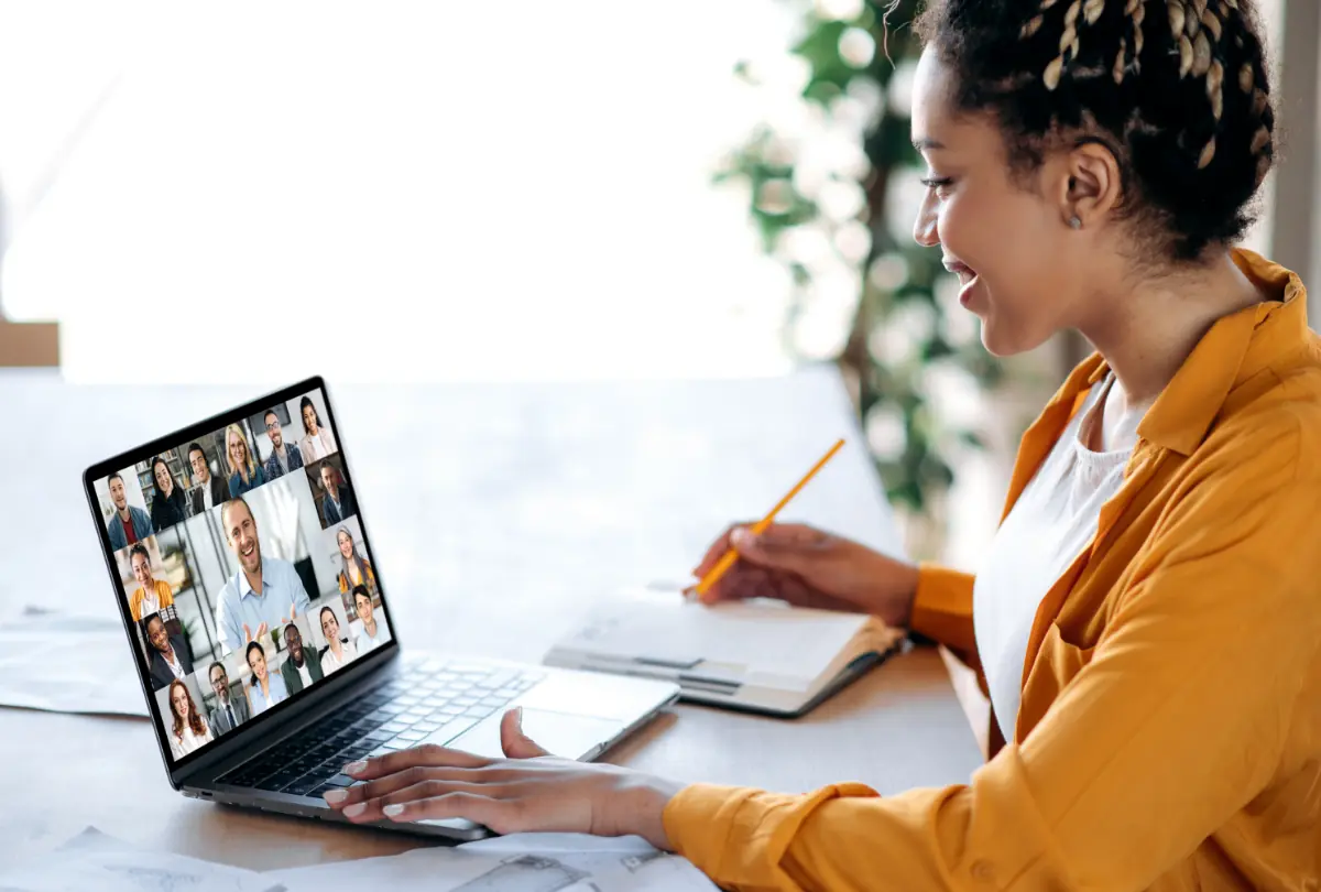 Séance d'information en ligne, conférence. Une gestionnaire afro-américaine communique avec l'équipe commerciale lors d'un appel vidéo, écoute un webinaire financier, prend des notes.
